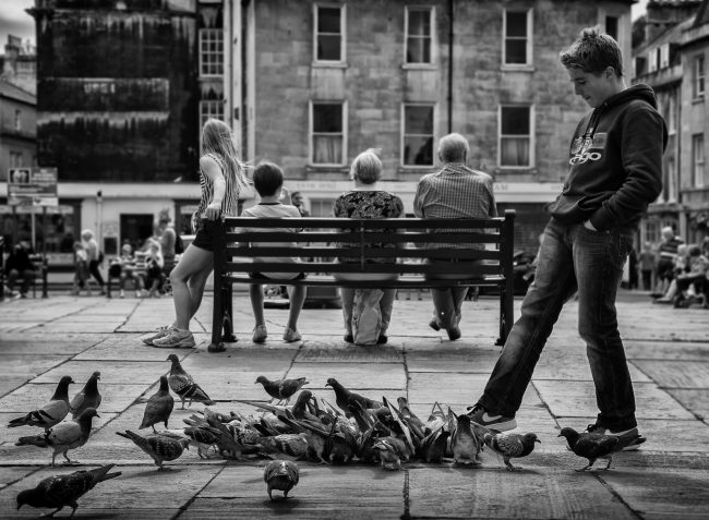 boy kicking at pigeons - UK street Photography